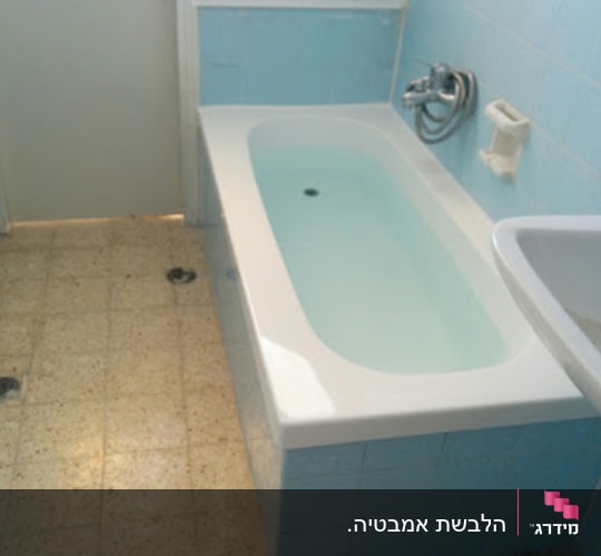 אמבטיה עם חיפוי אריחים כחולים וברז מתכת